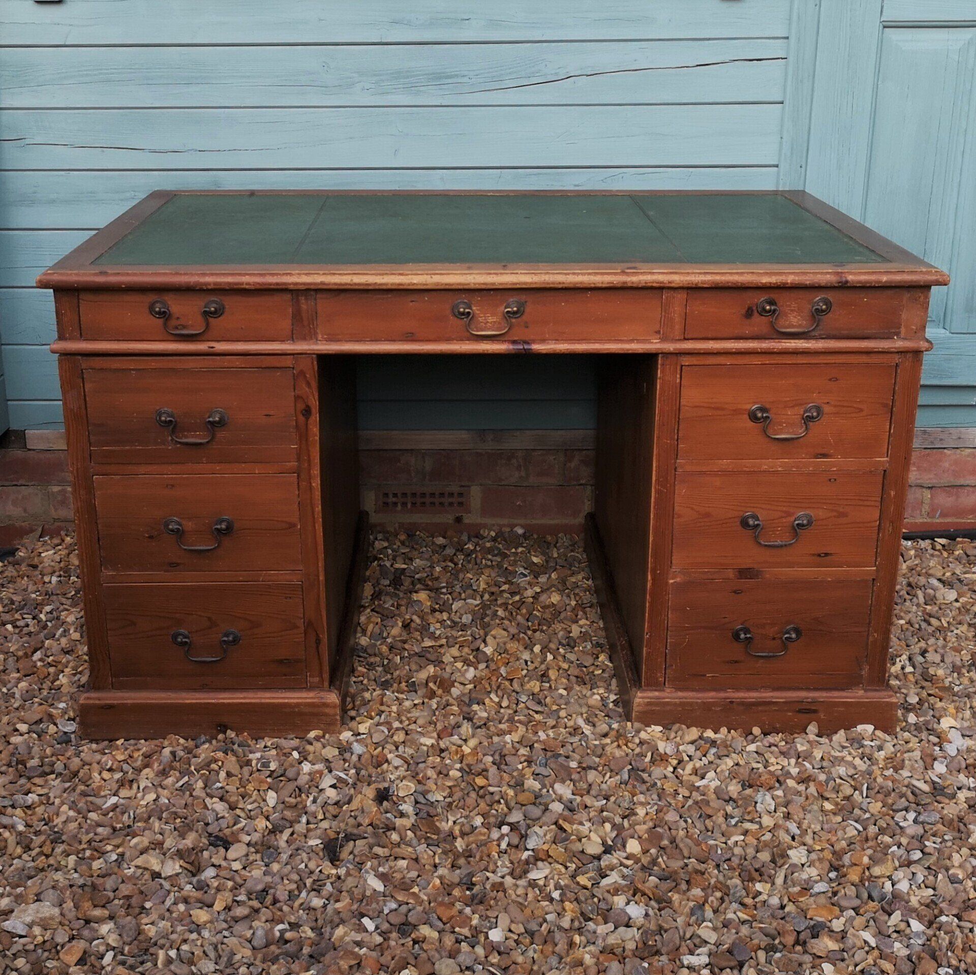 A wooden desk with drawers and a green leather top
