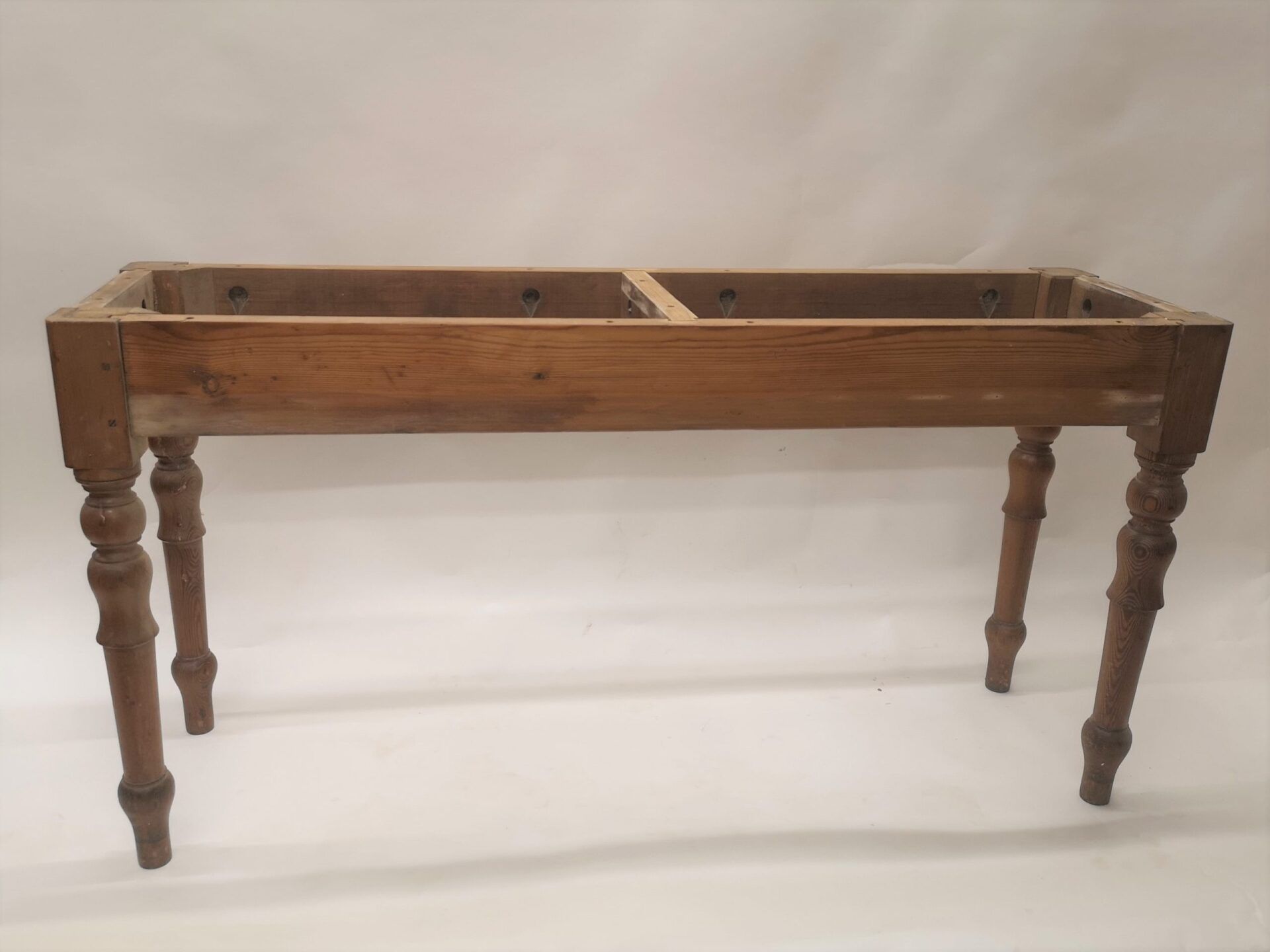 A wooden table with two legs is sitting on a white surface.