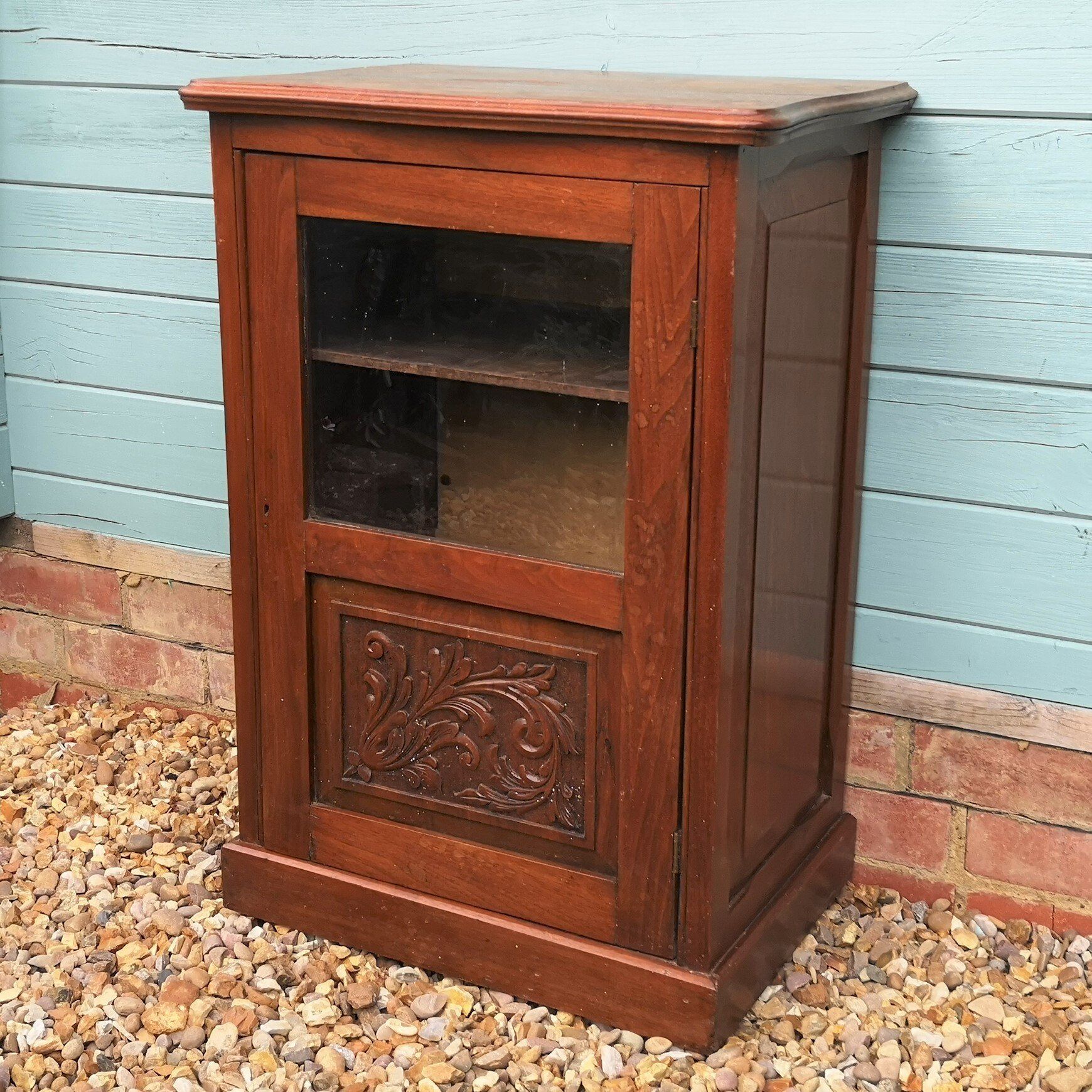 A small wooden cabinet with a glass door