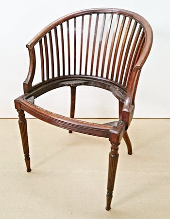A wooden chair without a seat is sitting on a carpeted floor.