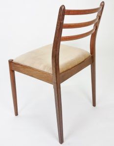 The back of a wooden chair with a beige cushion