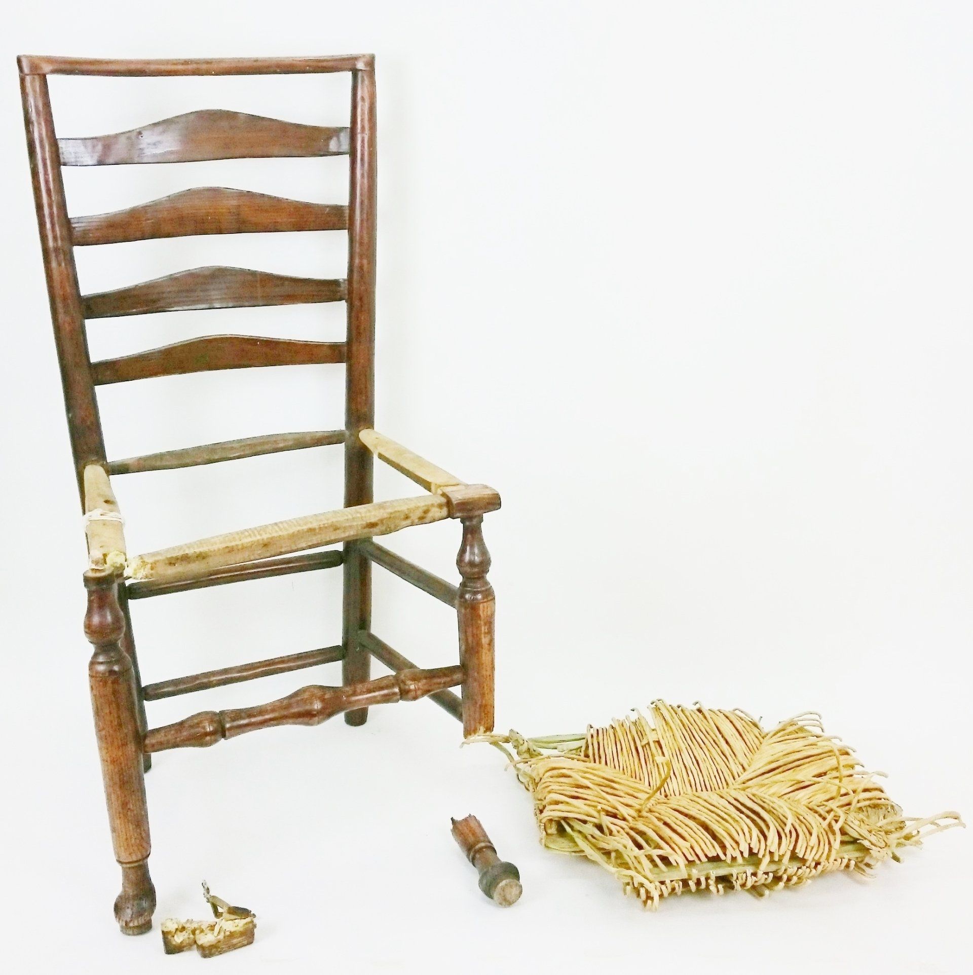 A wooden chair with a wicker seat is being repaired