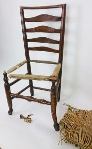 A wooden chair with a wicker seat is sitting on a white surface.