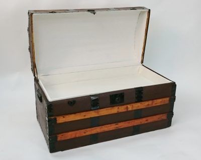A brown trunk with the lid open on a white surface