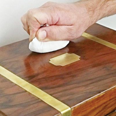 A person is polishing a wooden box with a white cloth