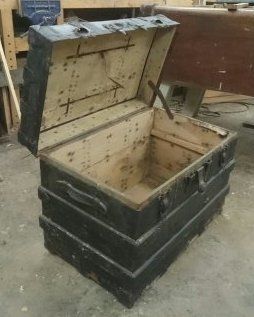 An old wooden trunk with the lid open is sitting on the floor.