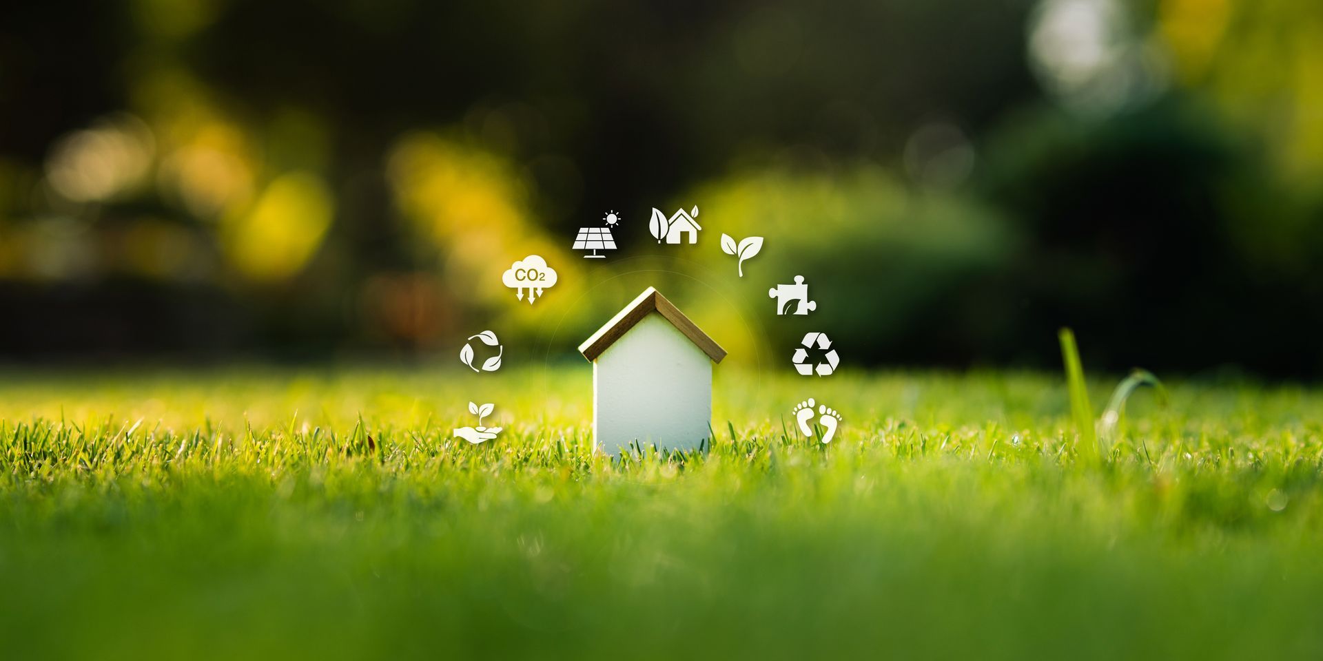 a small white house model placed on green grass with blurred natural background