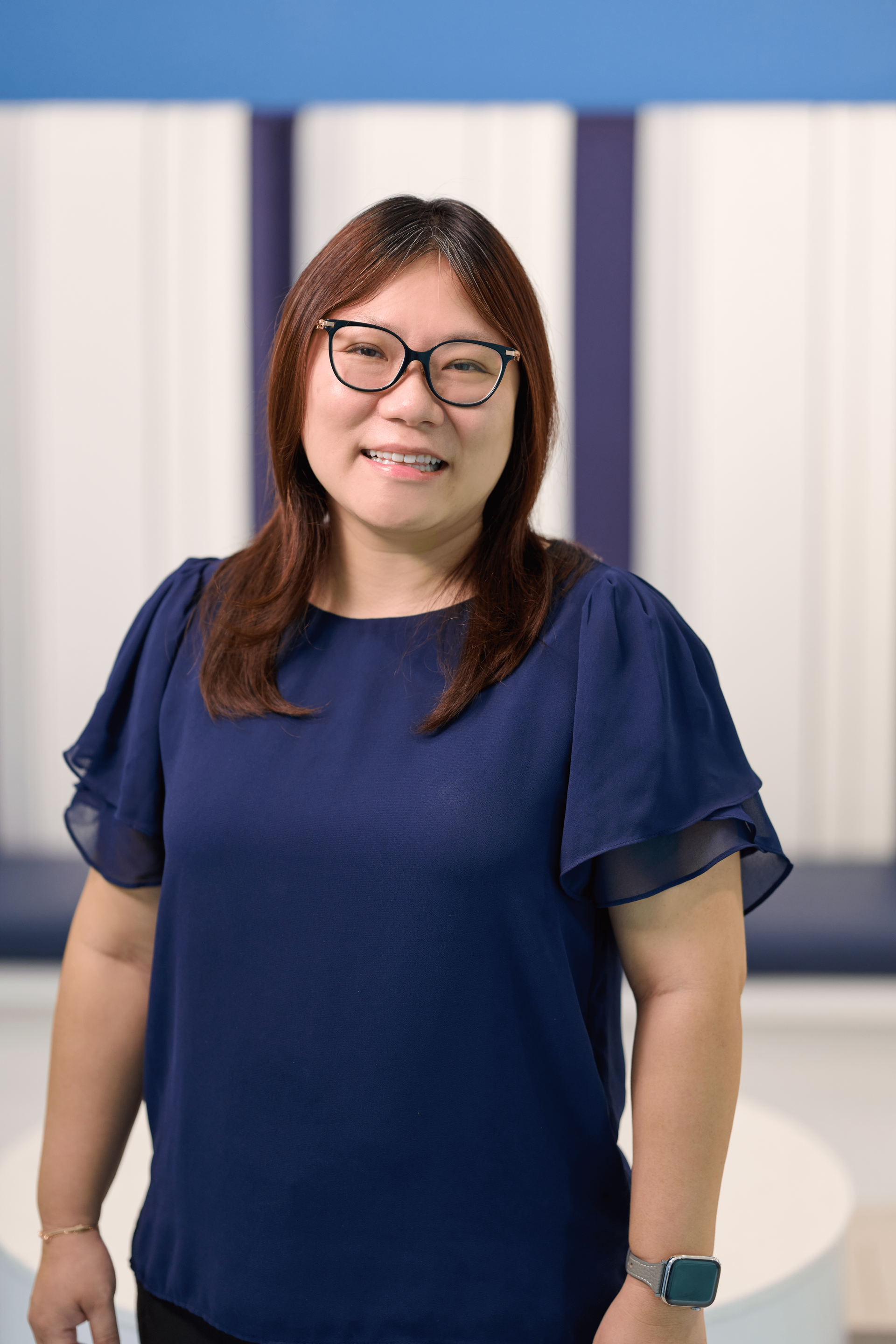 Ying Chen, Tax Division Leader of N&K CPA accounting firm, standing in front of a white and blue background wearing a dark blue blouse and glasses.