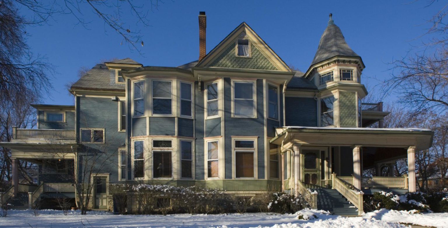 A large house with a lot of windows is covered in snow