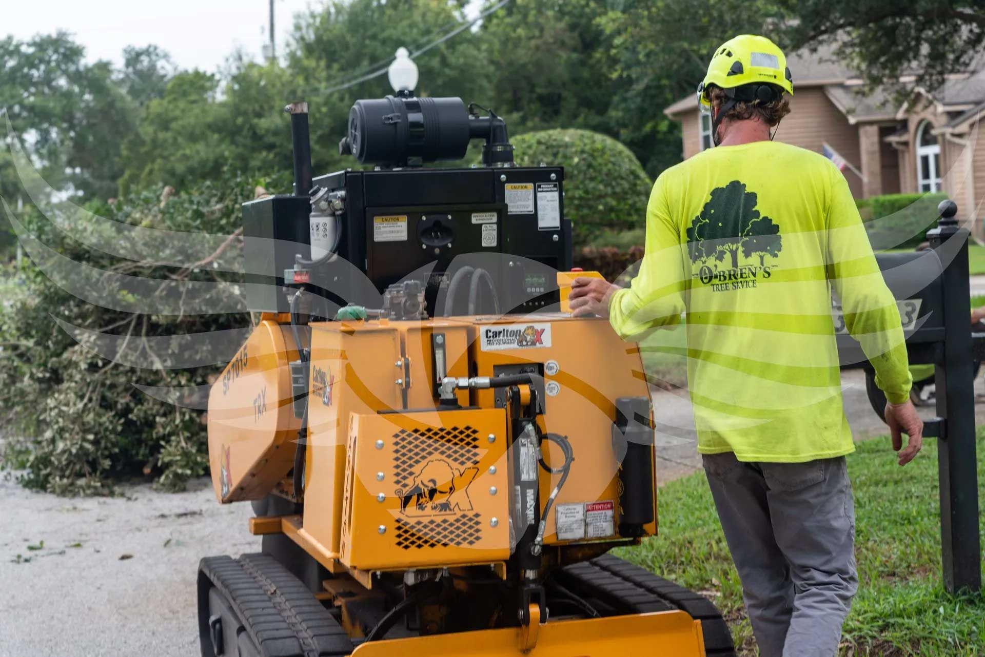A man in a yellow shirt is walking towards a tree chipper.