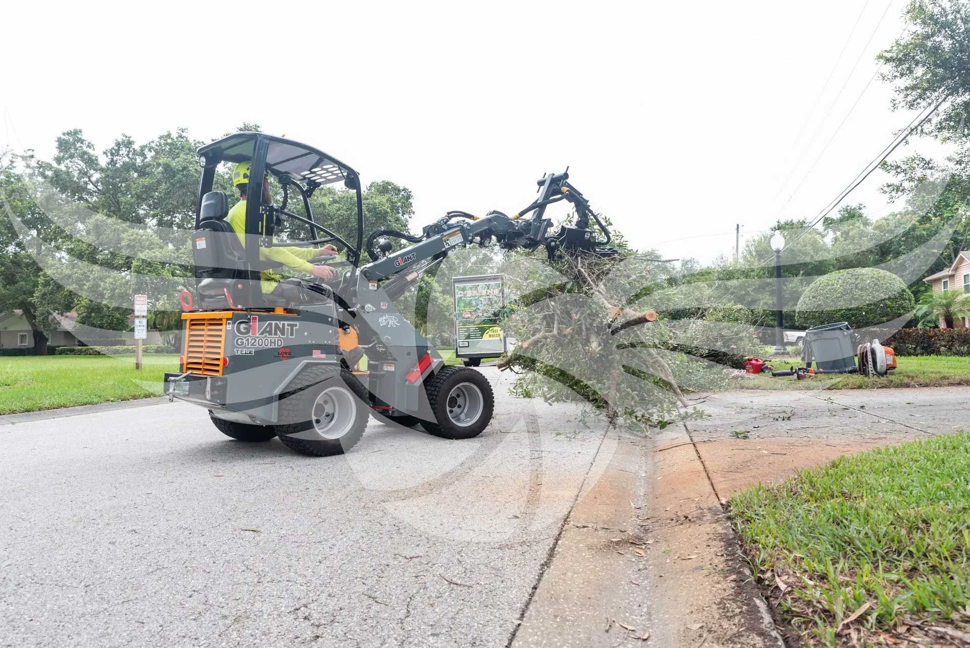 A bulldozer is clearing a tree from the side of the road.