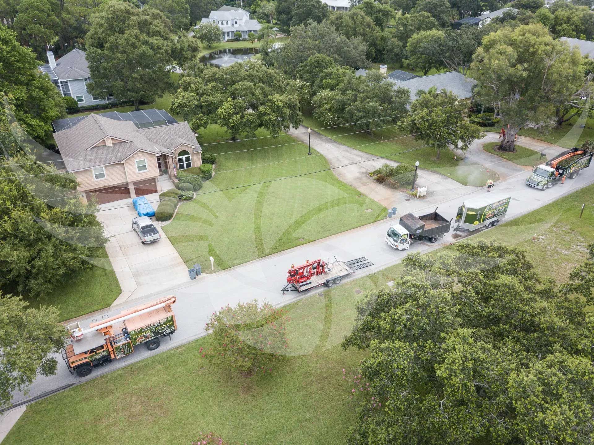 An aerial view of a residential neighborhood with trucks parked on the side of the road.