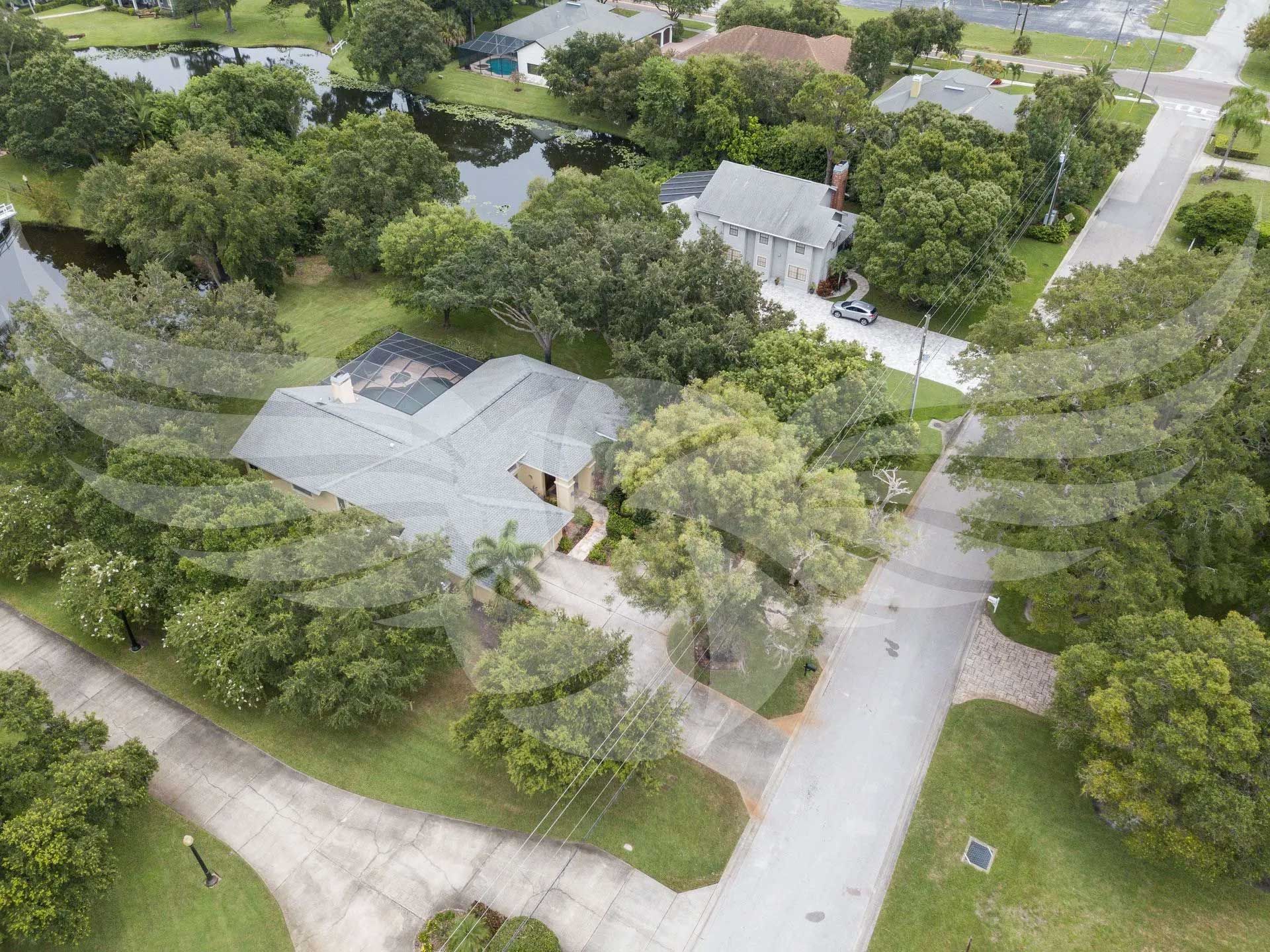 An aerial view of a house in a residential area surrounded by trees.