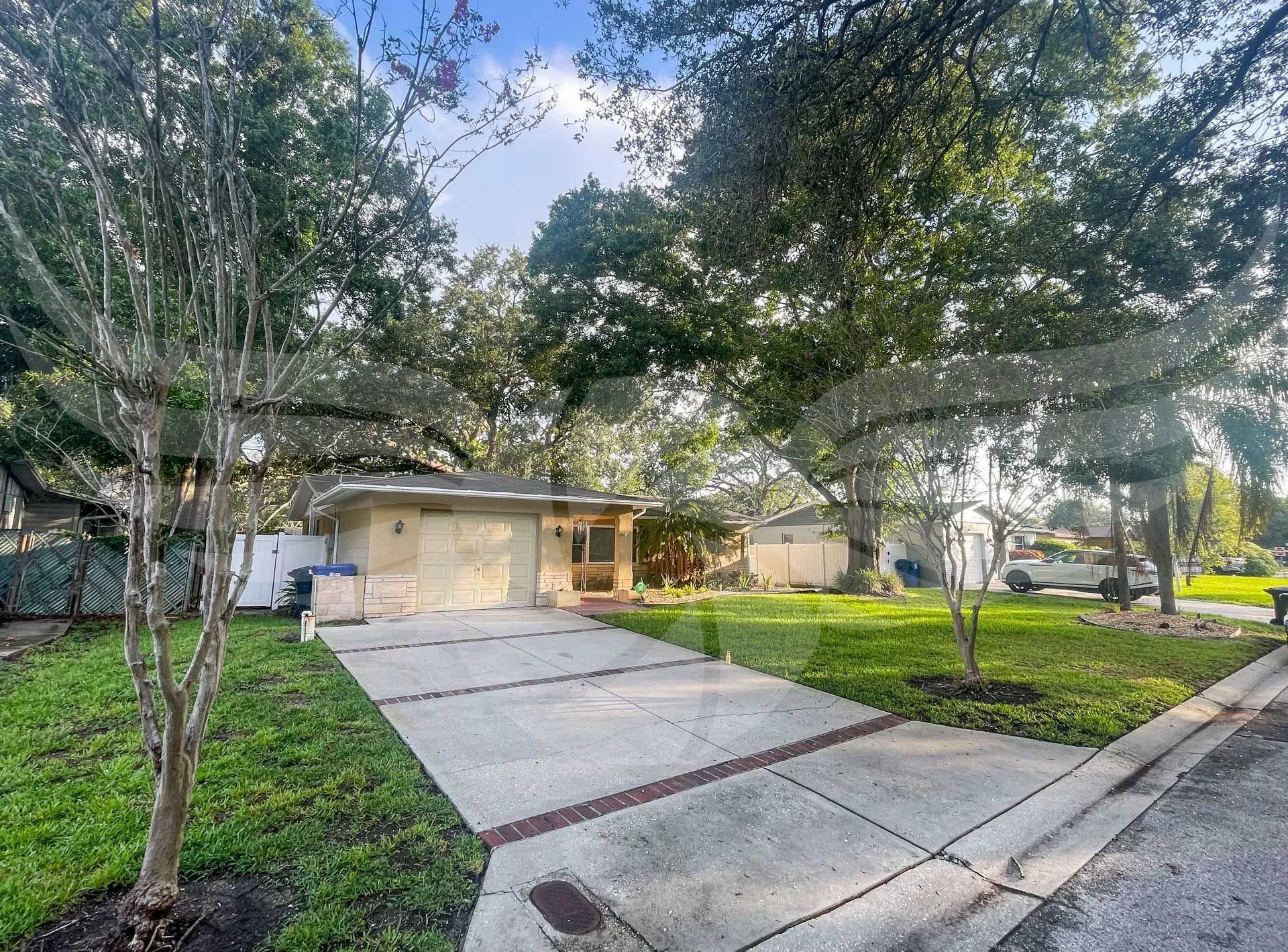 A house with a driveway and trees in front of it.