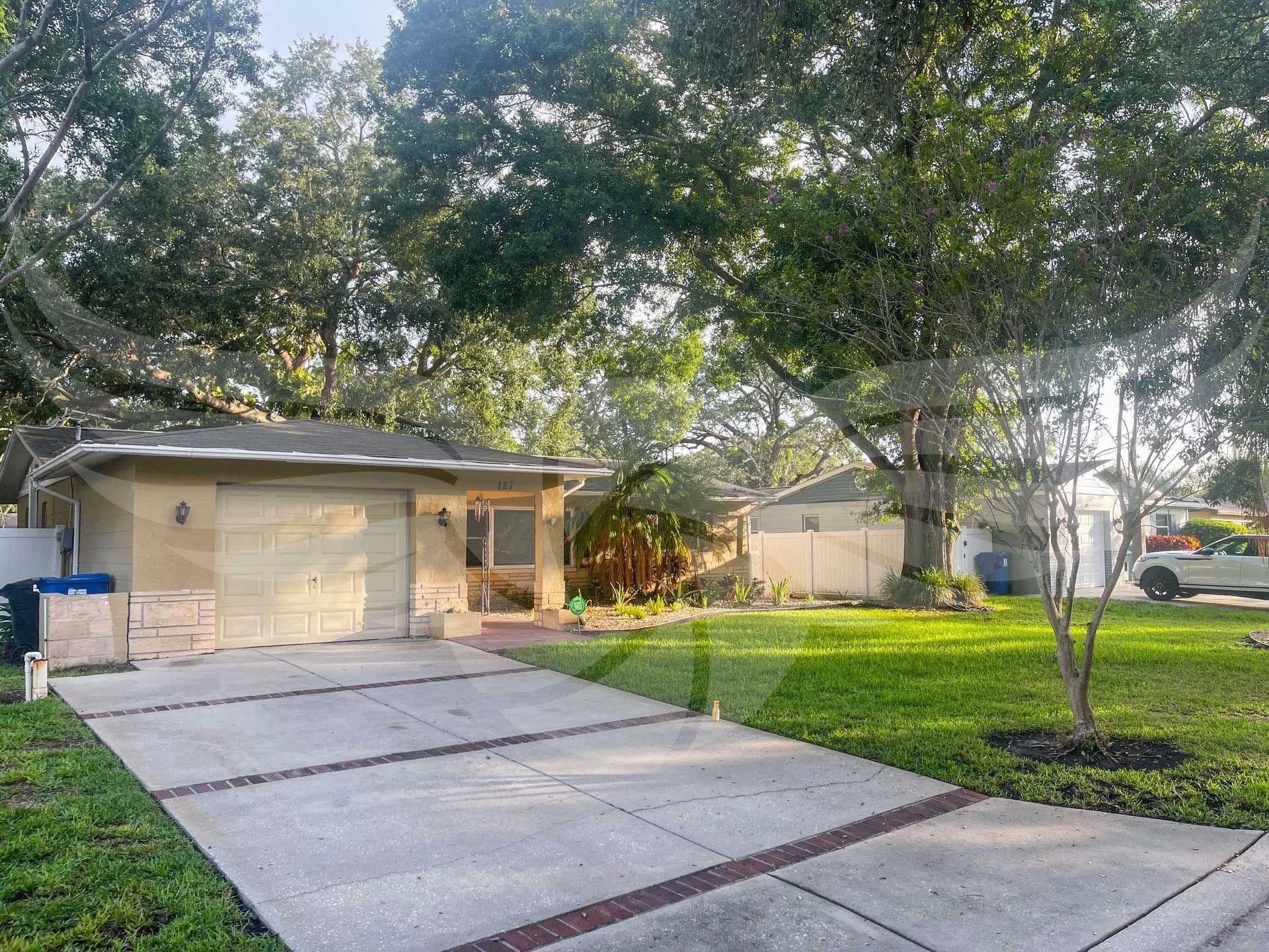 A house with a concrete driveway and a white van parked in front of it.