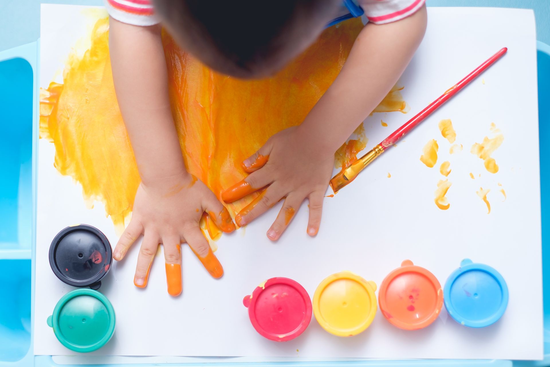 Young child finger painting during an art activity at Lobitos Family Daycare