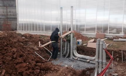 Two men are working on a greenhouse in the dirt.