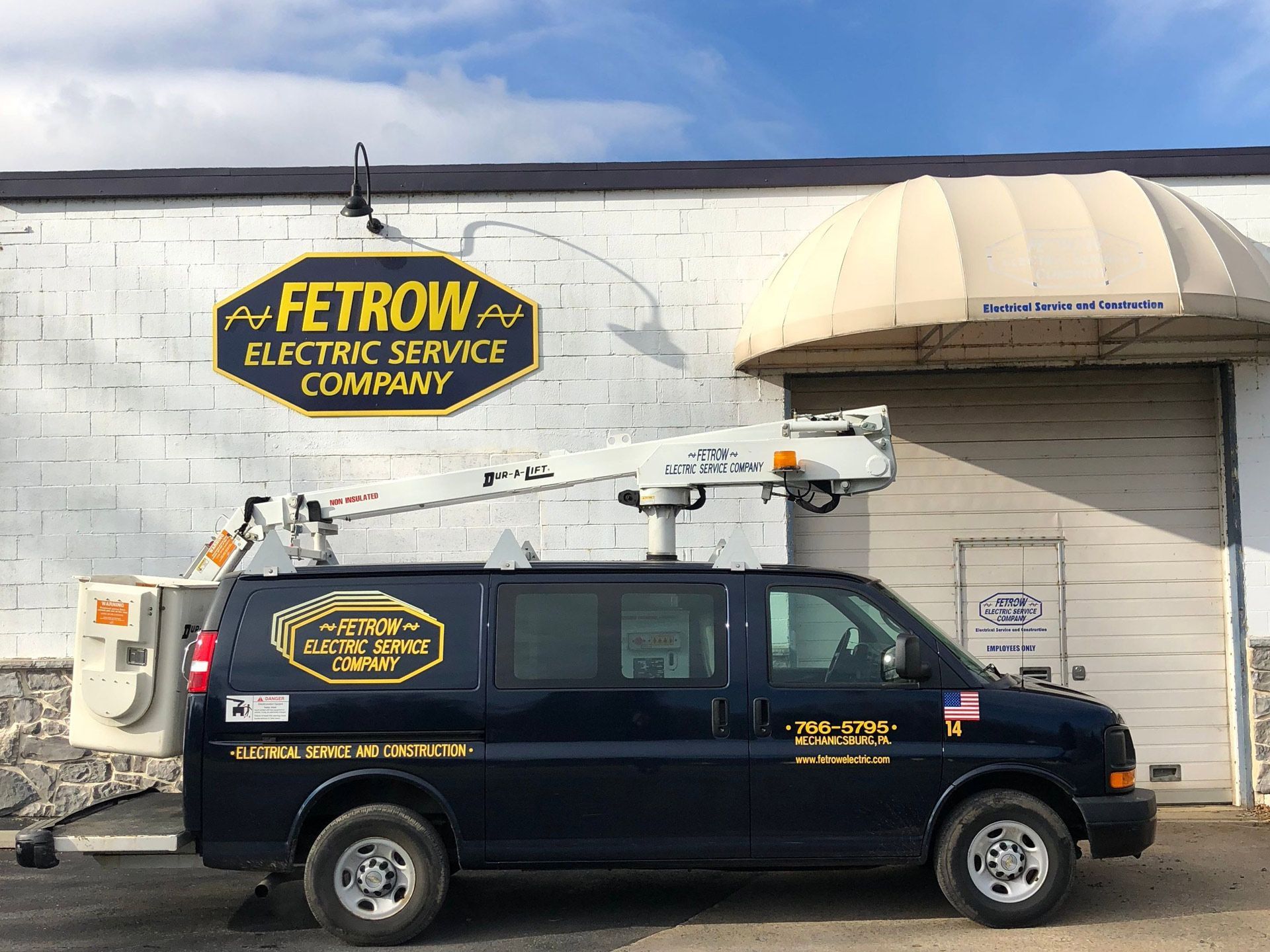 A black van is parked in front of a building that says fetrow electric service company