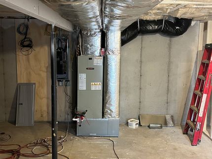A basement with a furnace and a red ladder.