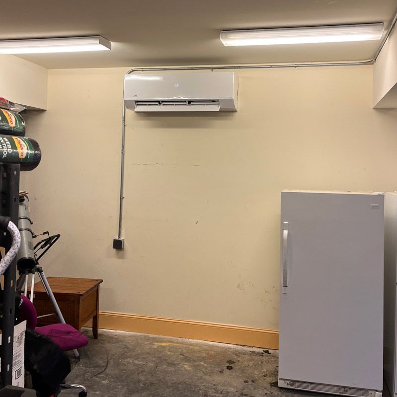 A white air conditioner is hanging on the wall next to a window.