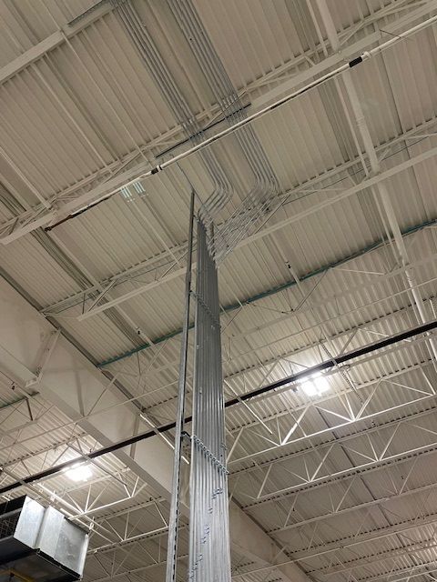 The ceiling of a large building with a lot of wires hanging from it.