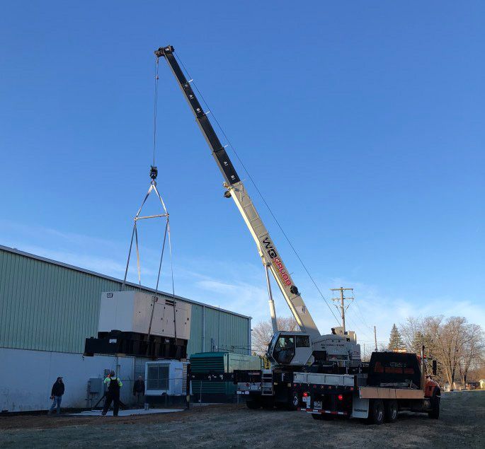 A large crane is lifting a container in front of a building