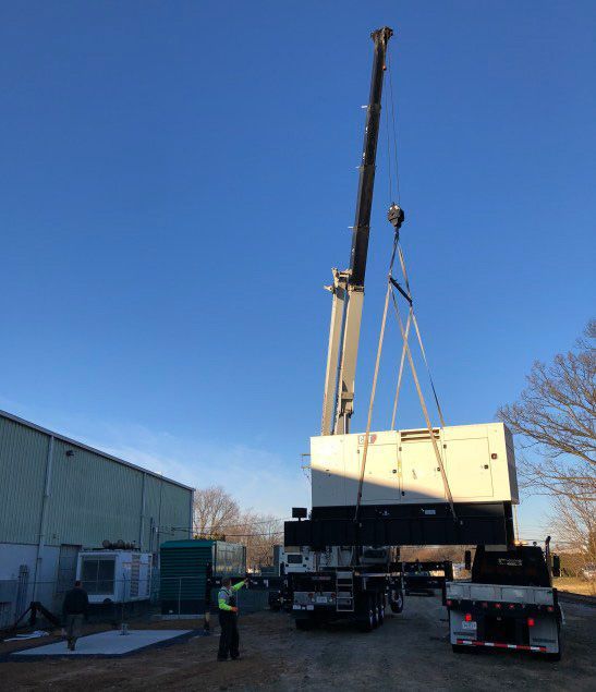 A truck is being lifted by a crane in a parking lot.