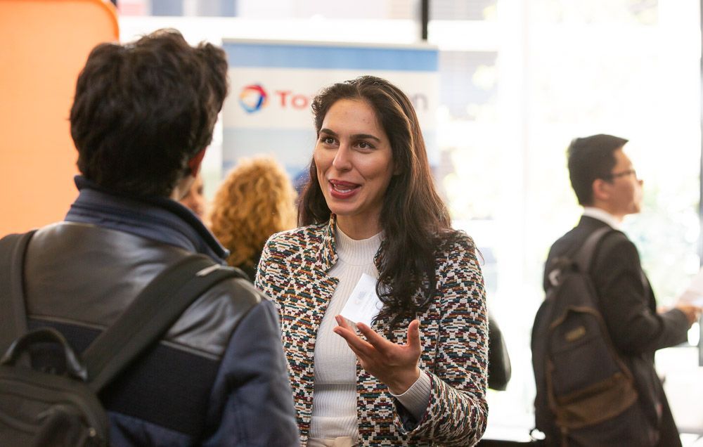 A woman is talking to a man in front of a total sign.