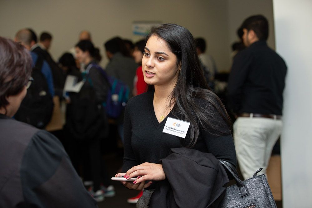 A woman is talking to another woman in a crowded room.
