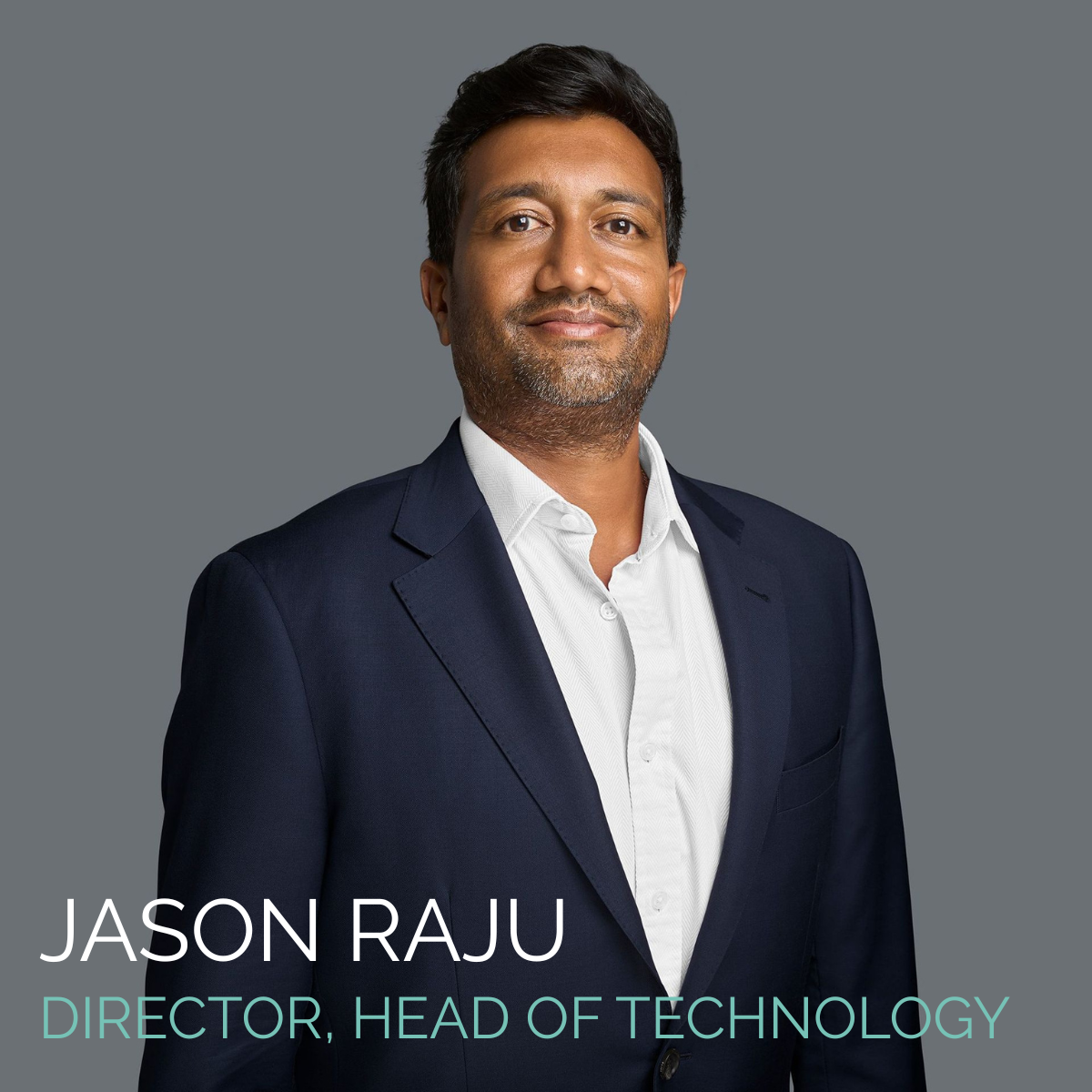 Jason Raju, Director, Head of Technology, smiles. He wears a navy suit jacket and a white shirt against a gray backdrop.
