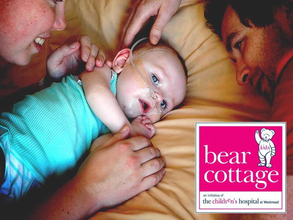 Bear Cottage A baby is laying on a bed next to a bear cottage logo
