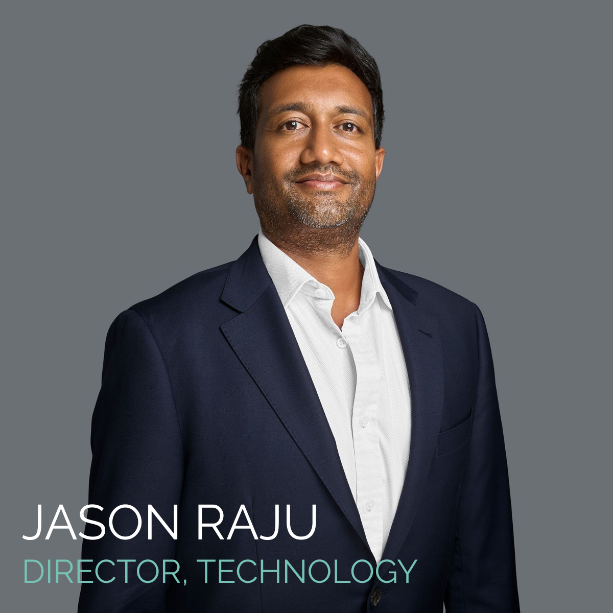 Jason Raju, Director of Technology, in a navy suit and white shirt, smiling against a gray background.
