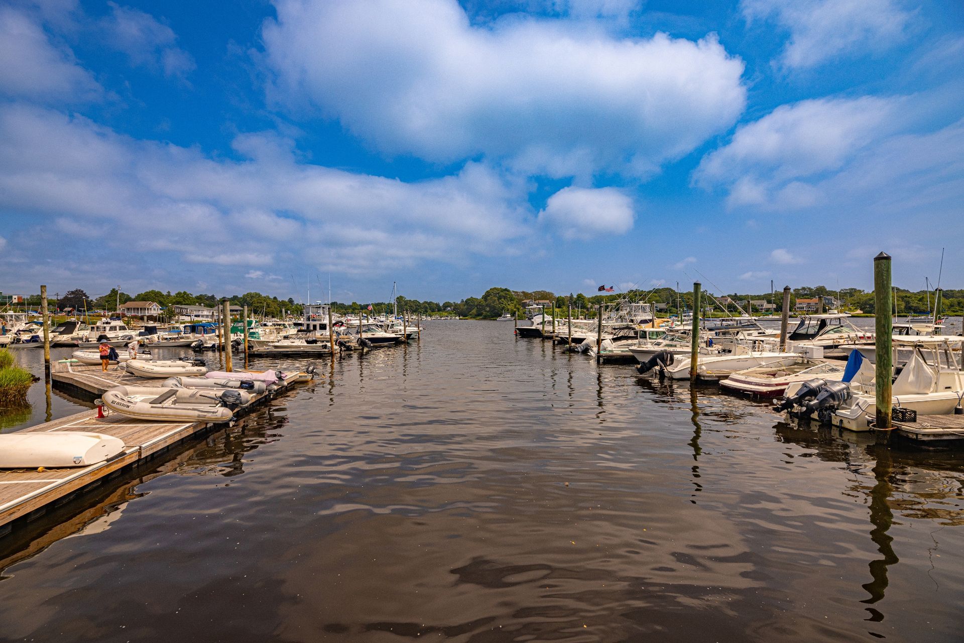 A row of boats are docked in a marina on a sunny day.