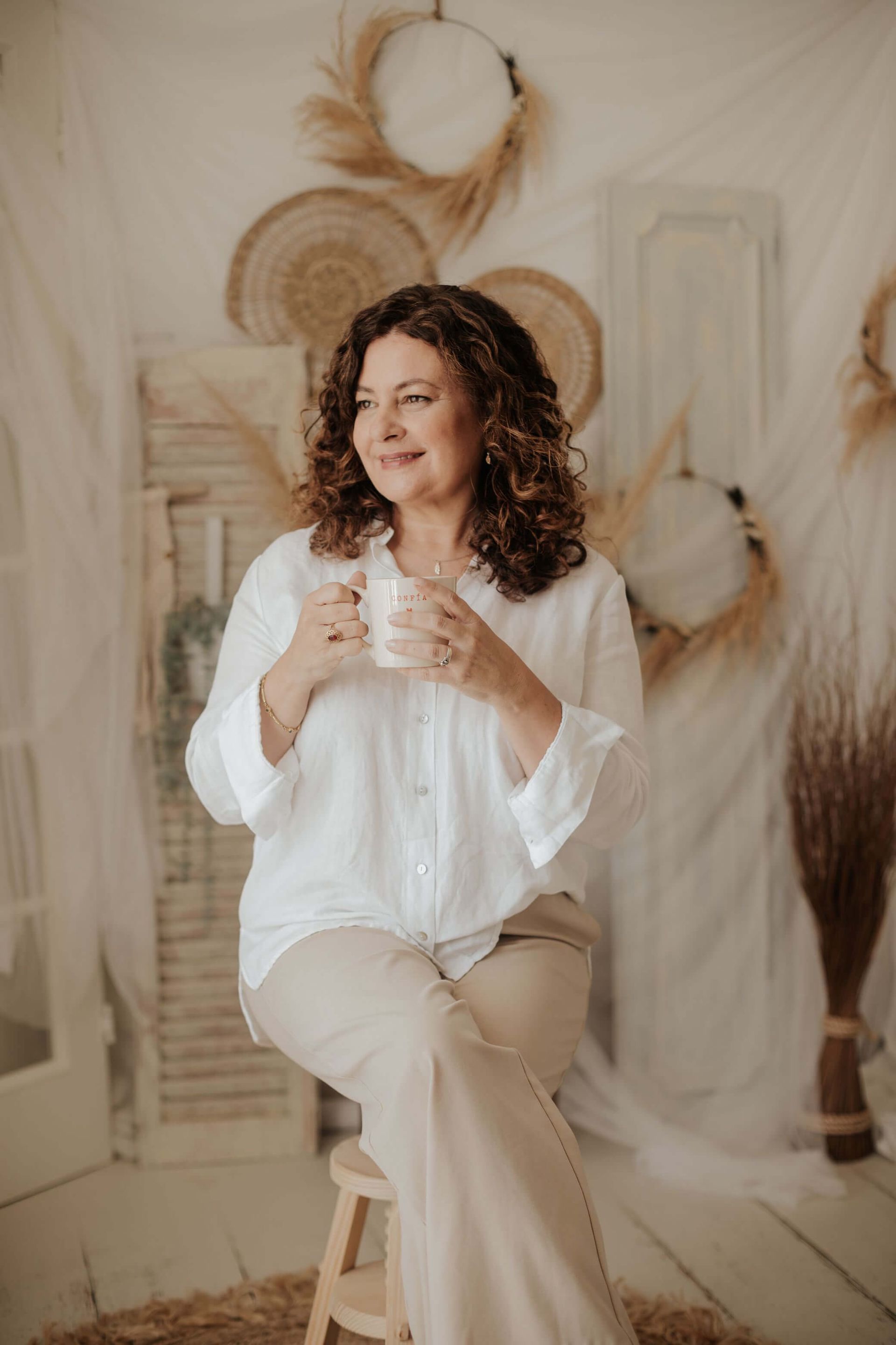 Mónica García Hidalgo está sentada en un taburete sosteniendo una taza de café.