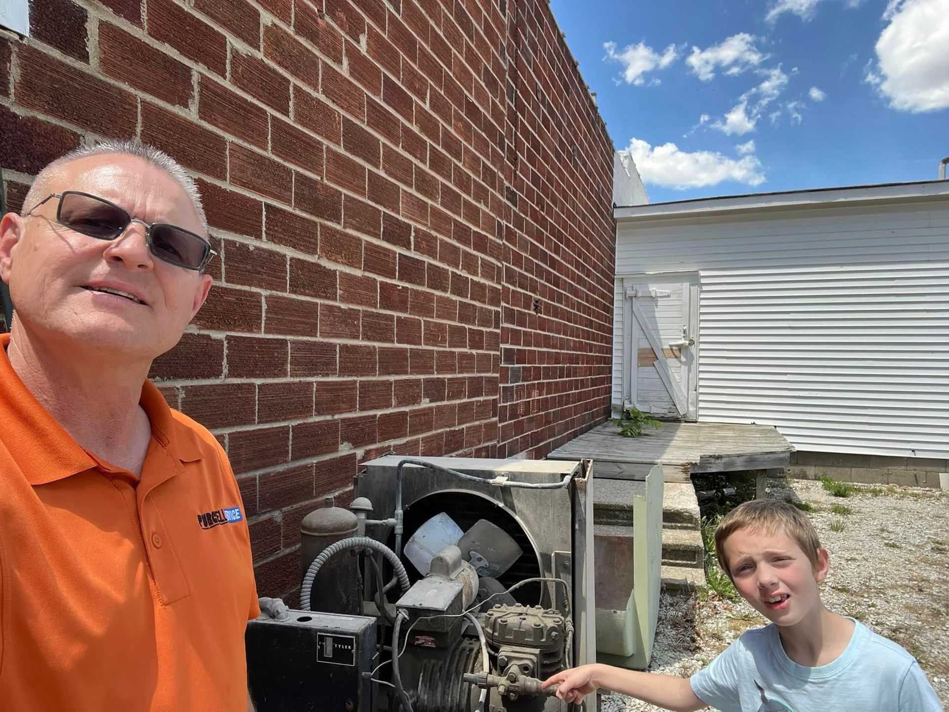 A man and a boy are standing next to a brick wall.