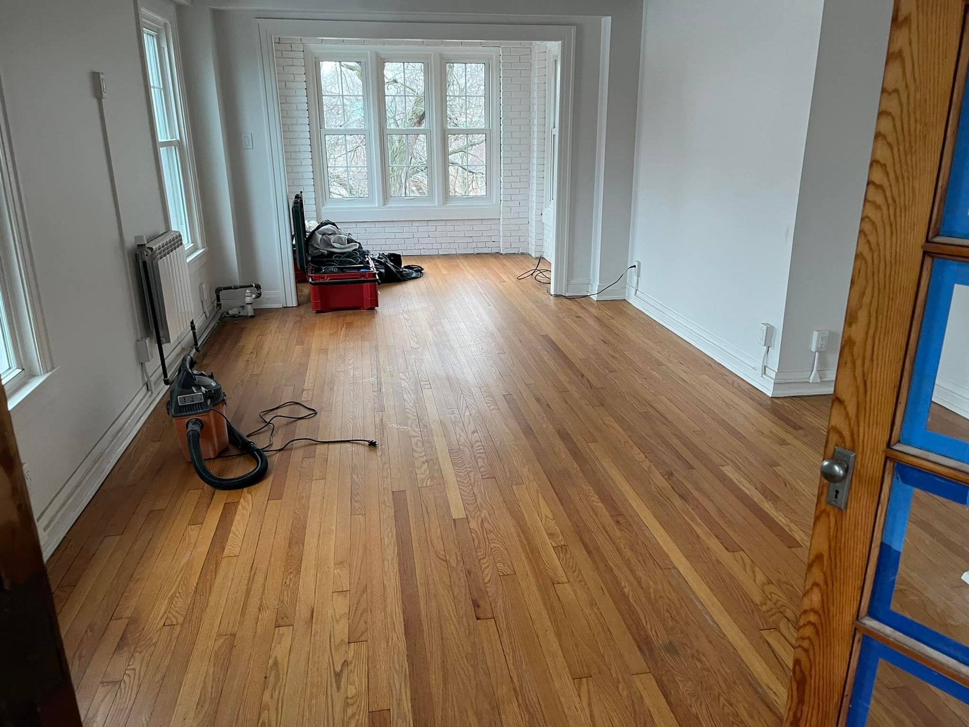 A living room with hardwood floors and a vacuum cleaner on the floor.