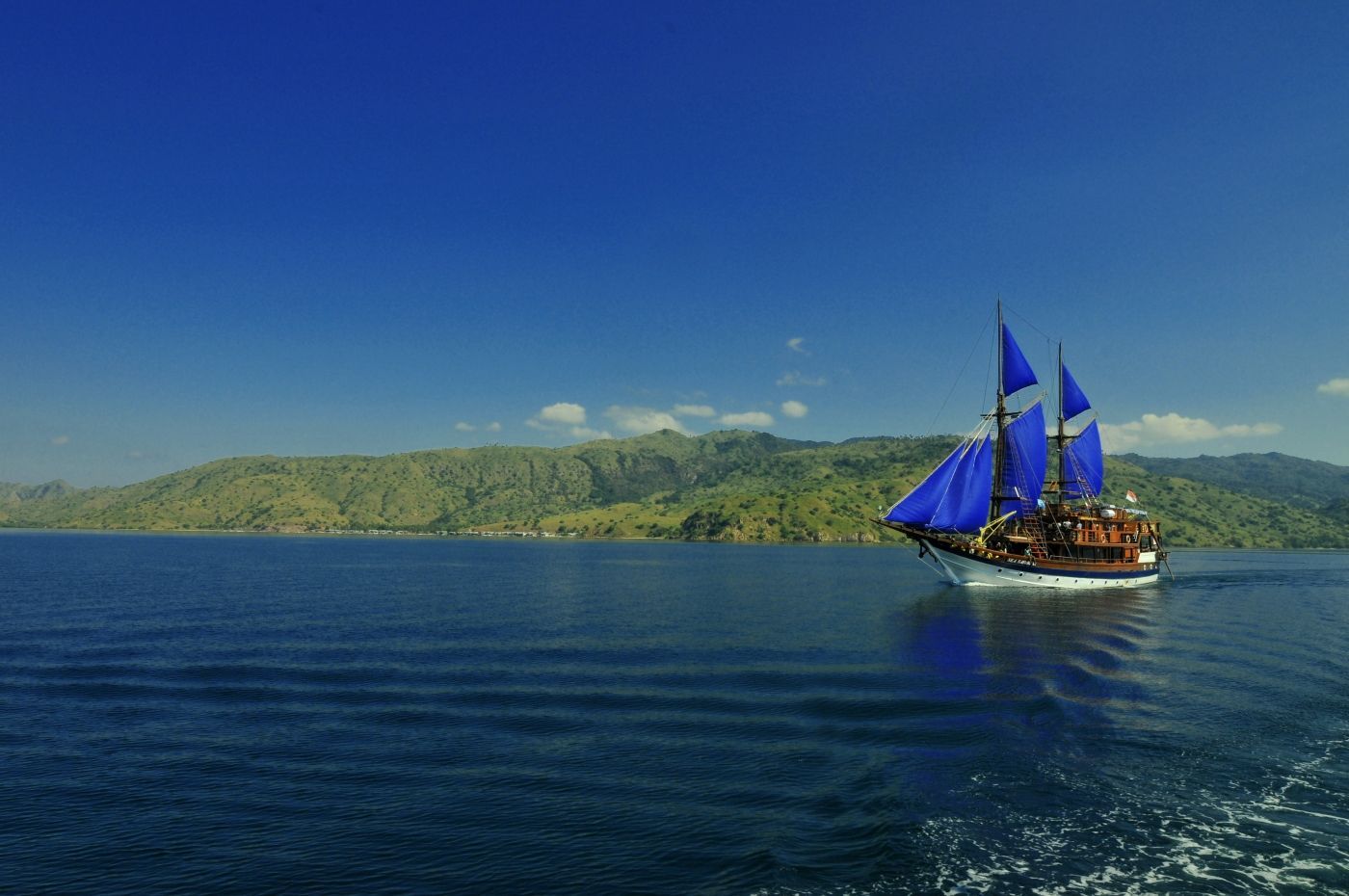 fotoVintage houten schip met blauwe zeilen in de buurt komodo island