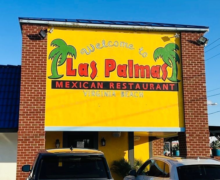 Las Palmas Mexican Restaurant exterior, yellow sign with palm trees, red and black text, brick facade, cars in front.