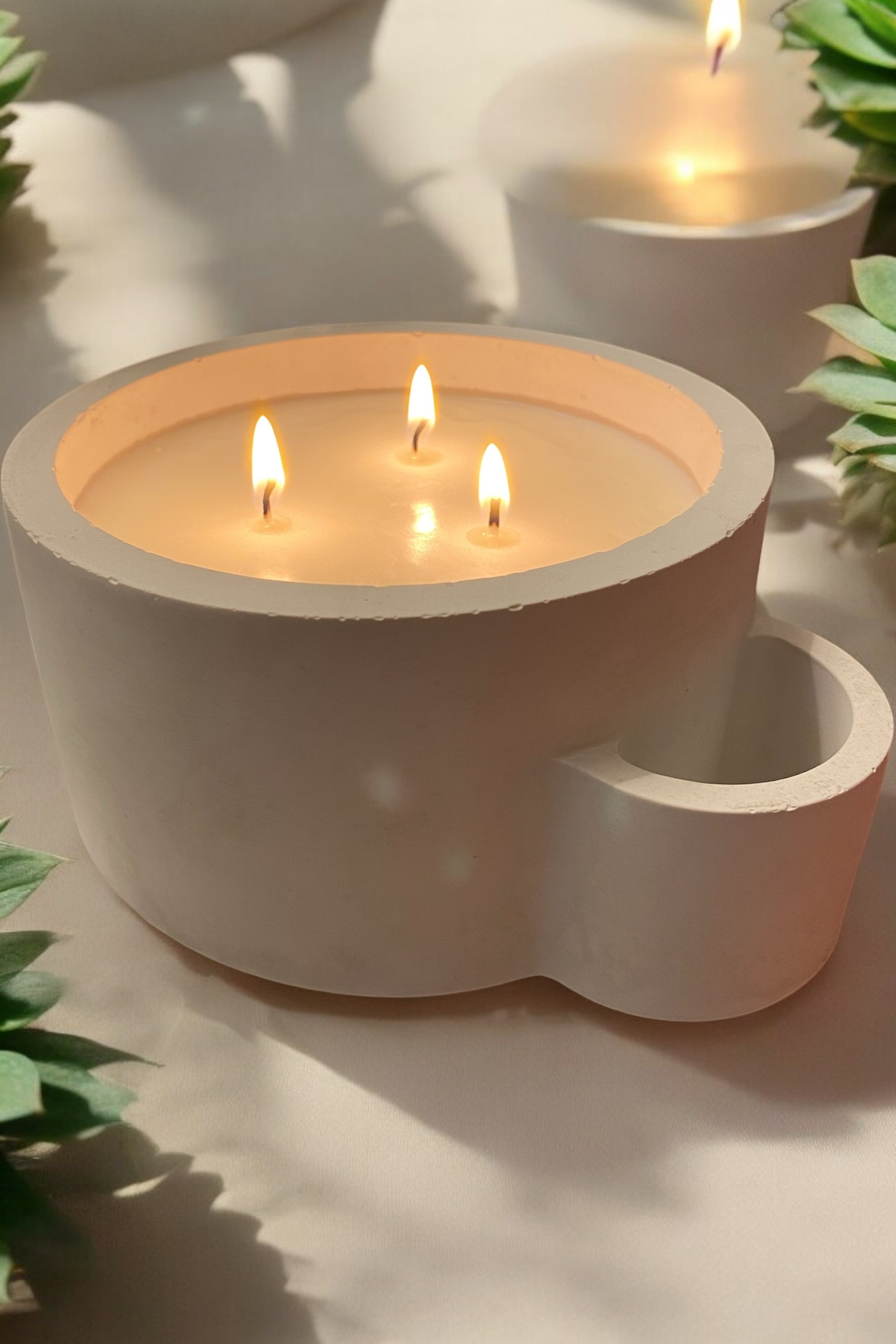 Three candles are lit in a white bowl on a table