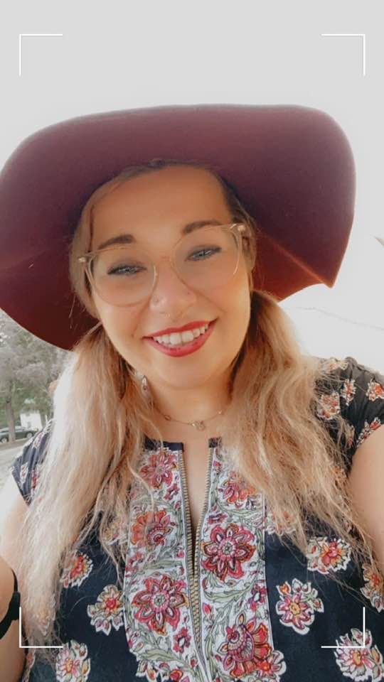 A woman wearing a red hat and glasses is smiling.