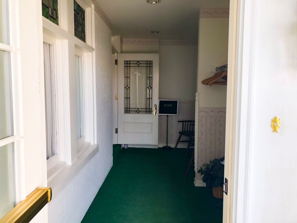 A hallway with a green carpet and a white door