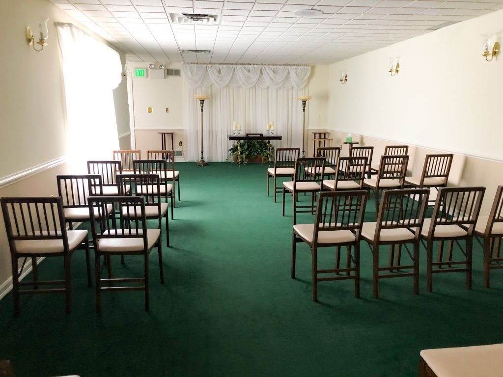 A row of chairs are lined up in a room with a green carpet.