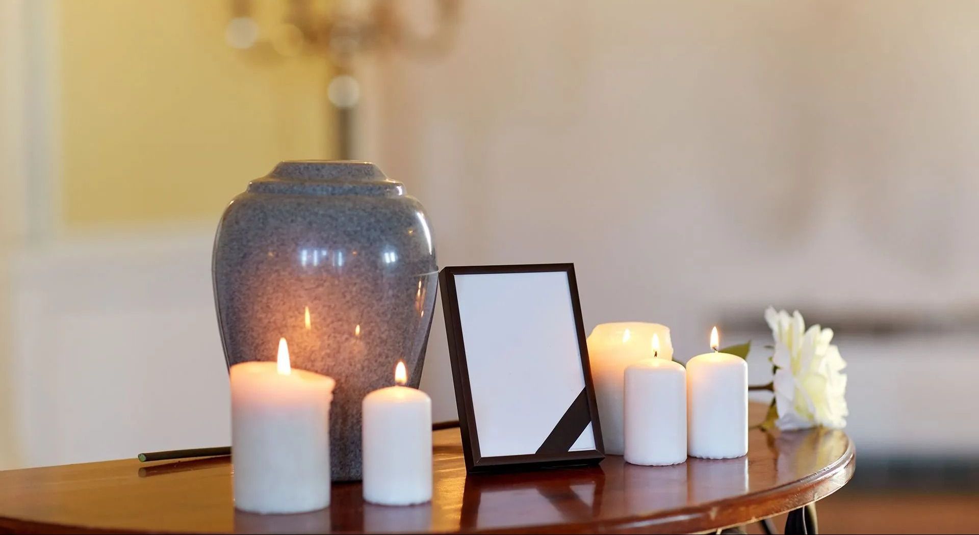 A table with candles , a picture frame , and a vase on it.
