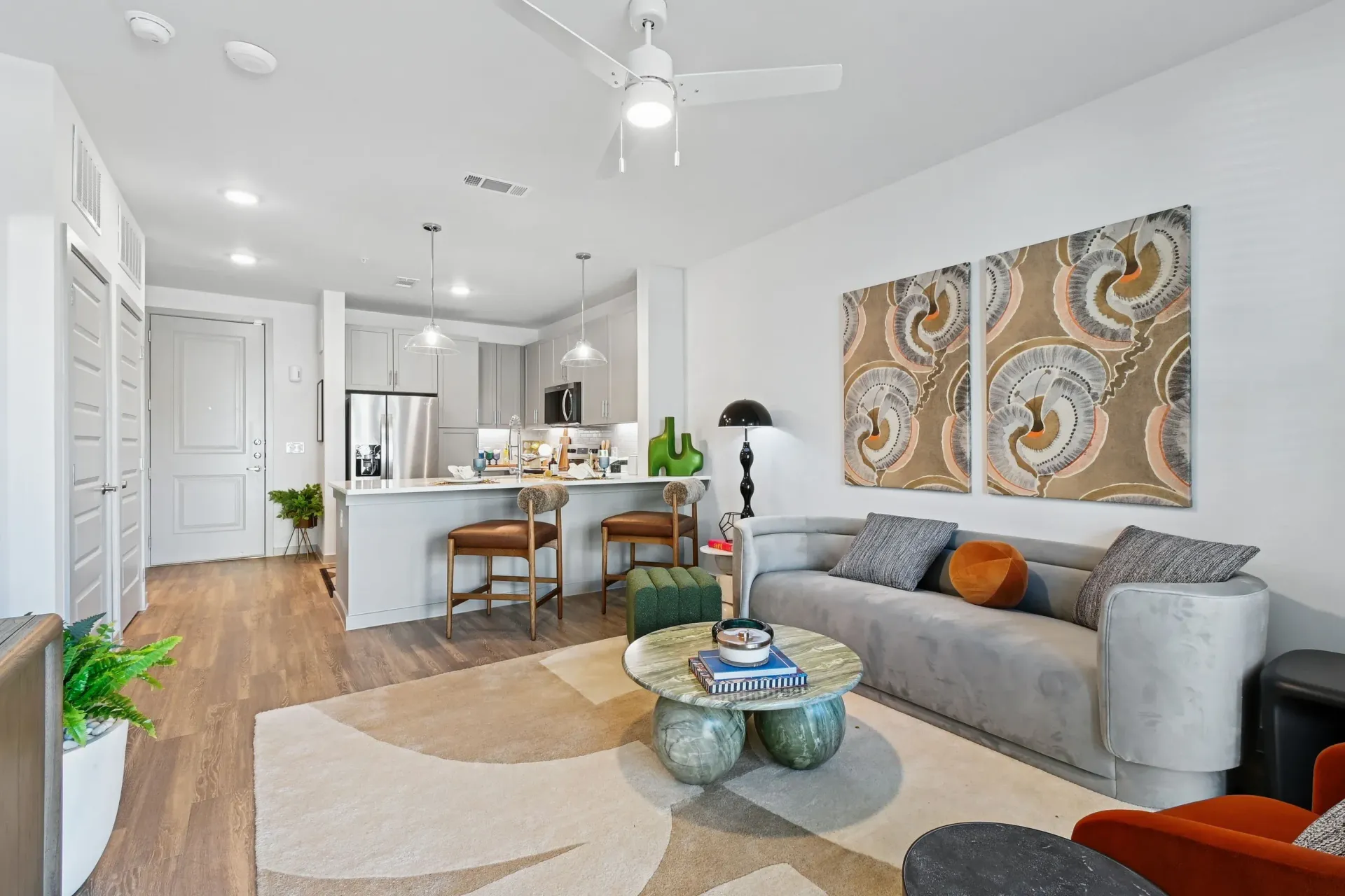 Open-concept living area with a gray sofa, coffee table, and a kitchen island with stools.