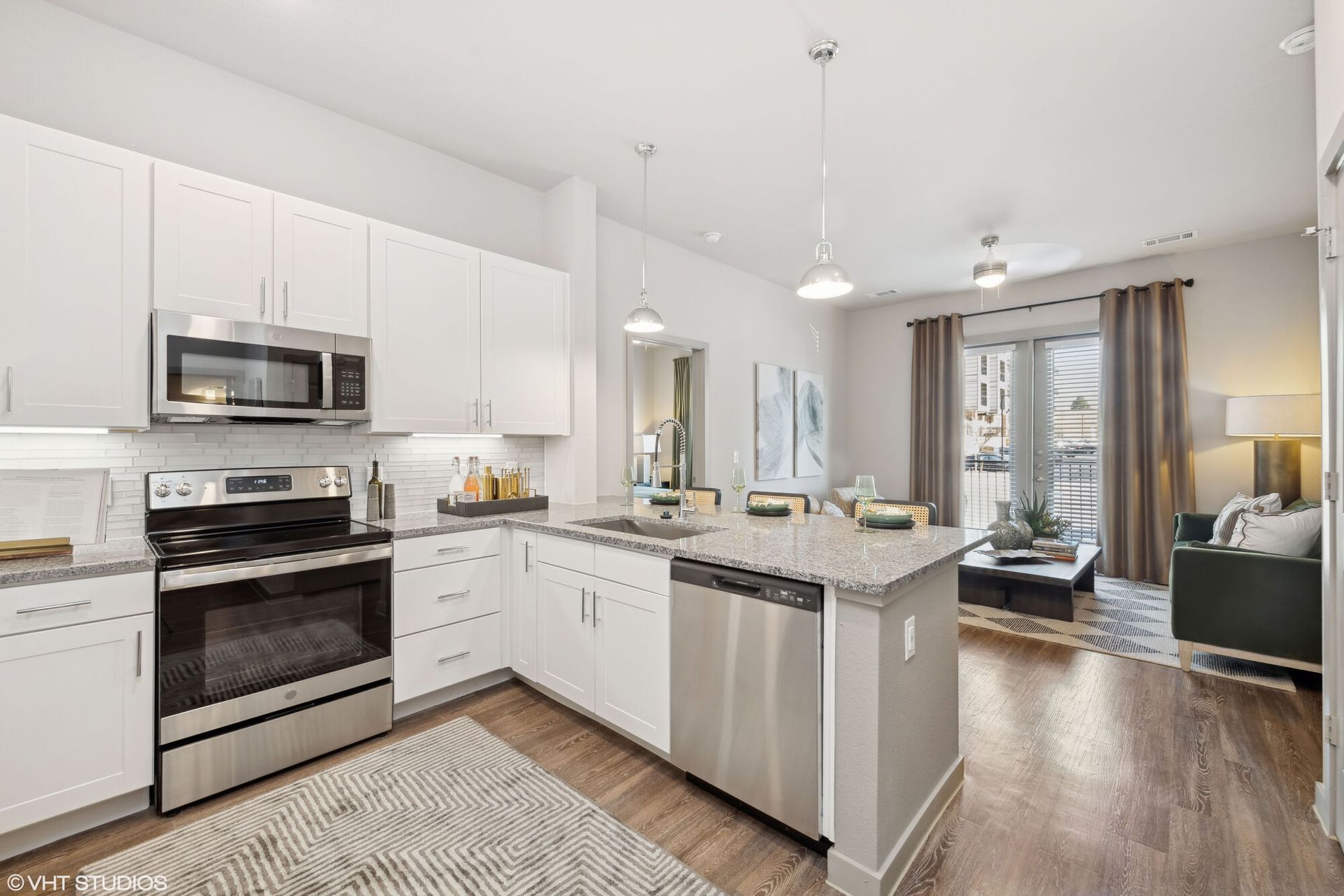 Open-concept kitchen with white cabinets and stainless steel appliances in an open living space.