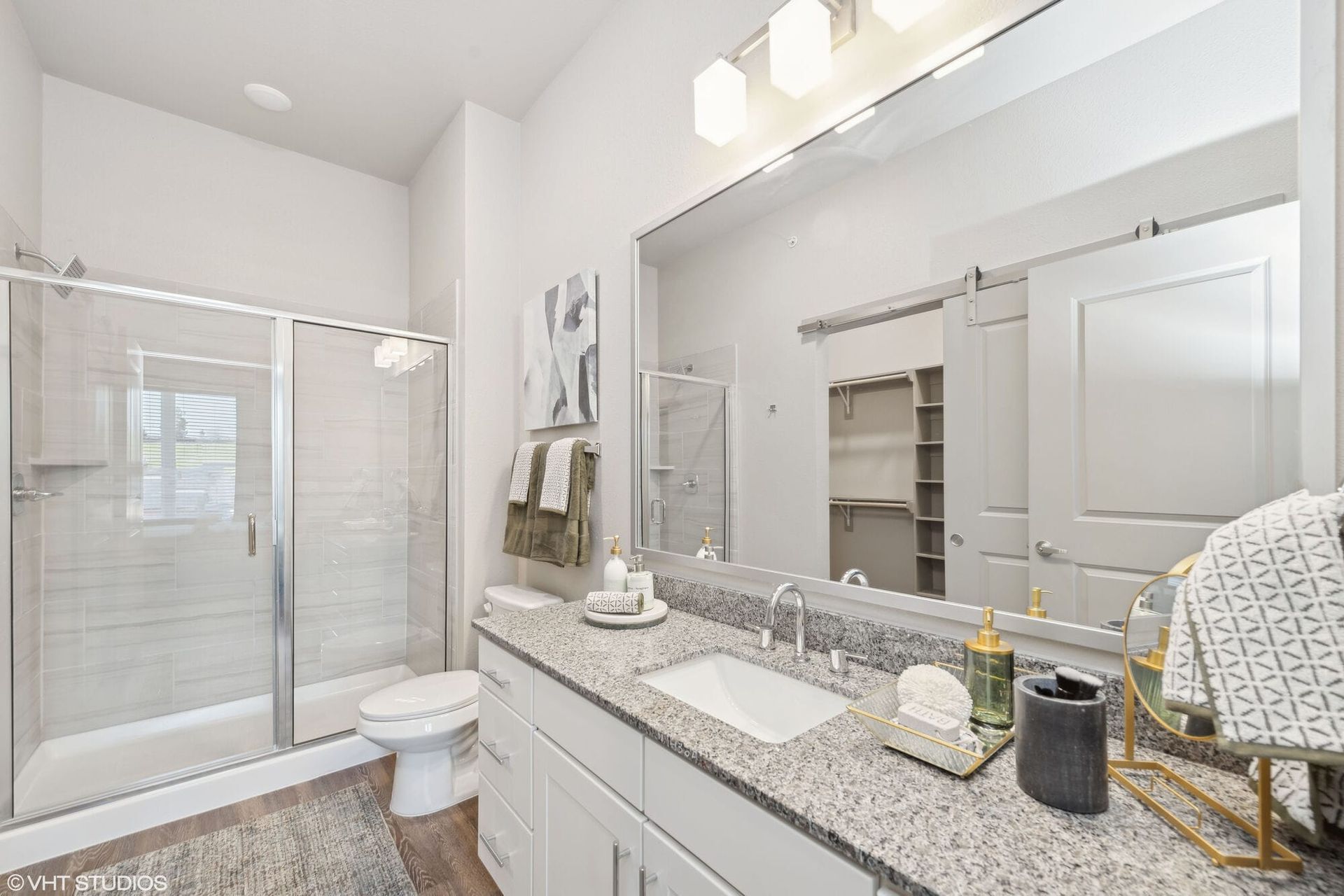 Bathroom with granite vanity, large mirror, and glass-enclosed shower.