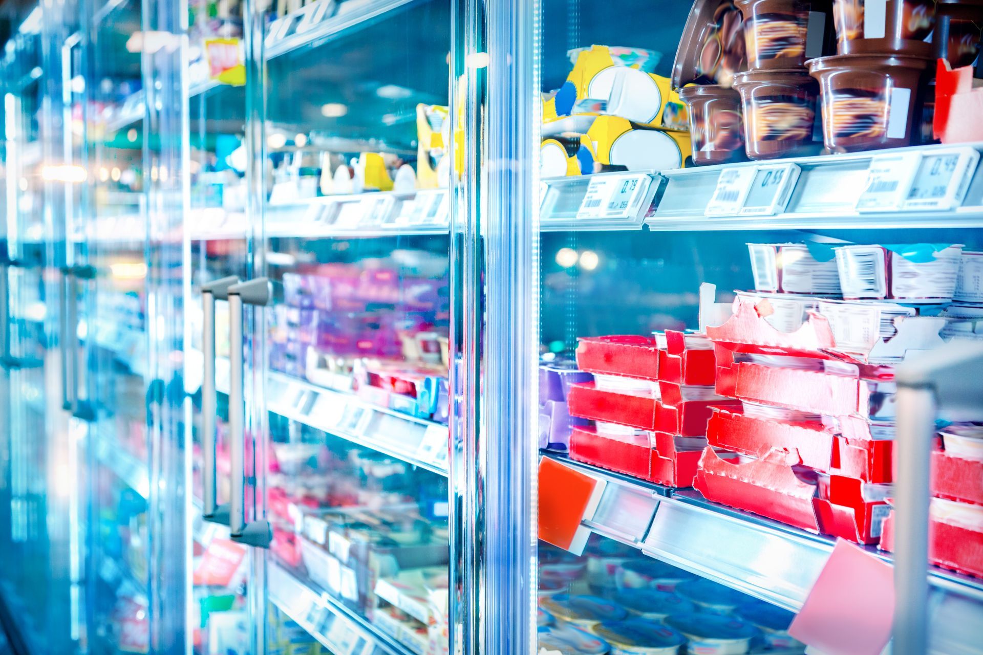 Refrigerator case in a grocery store, full of various packaged food items with glass door. Refrigerator case in a grocery store, full of various packaged food items with glass door.
