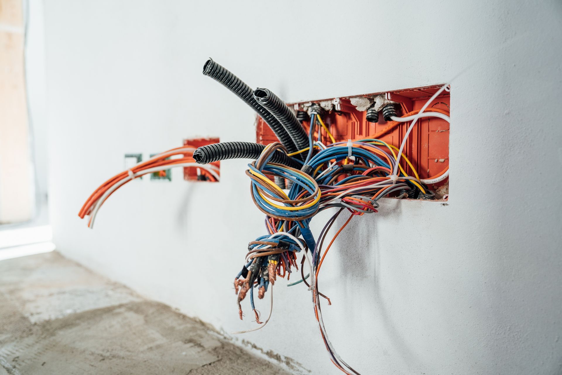 Exposed electrical wiring in a red box on a white wall; various colored wires are visible.