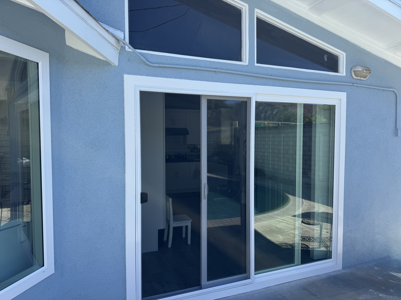 Blue exterior wall with sliding glass patio doors and upper windows on a house