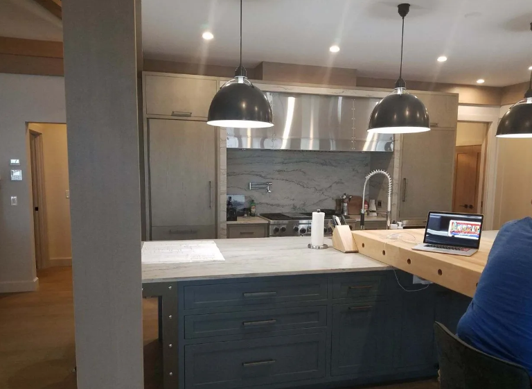 A kitchen with a large island and a laptop on the counter